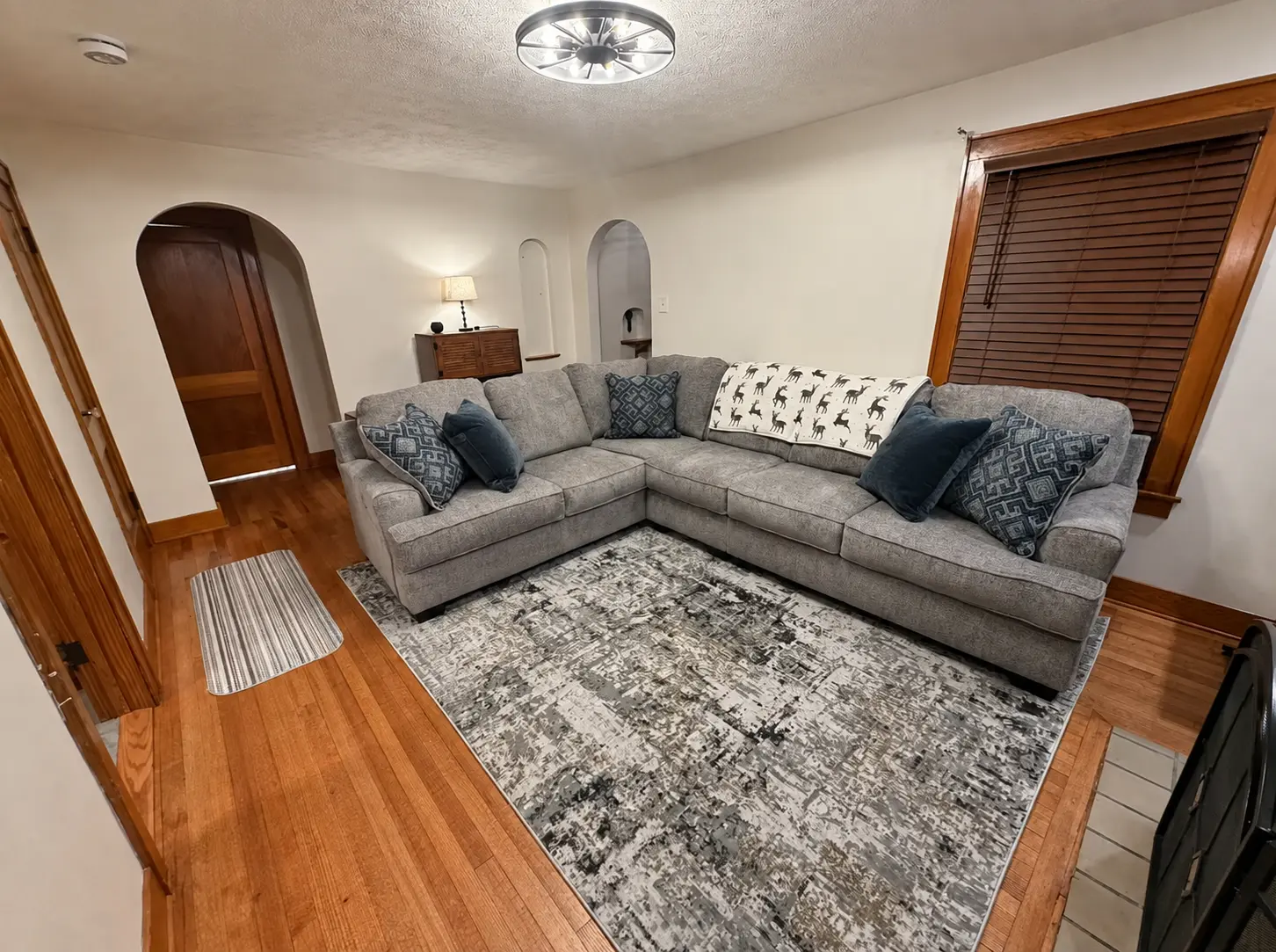 Living room with a gray sectional sofa, area rug and hardwood floors