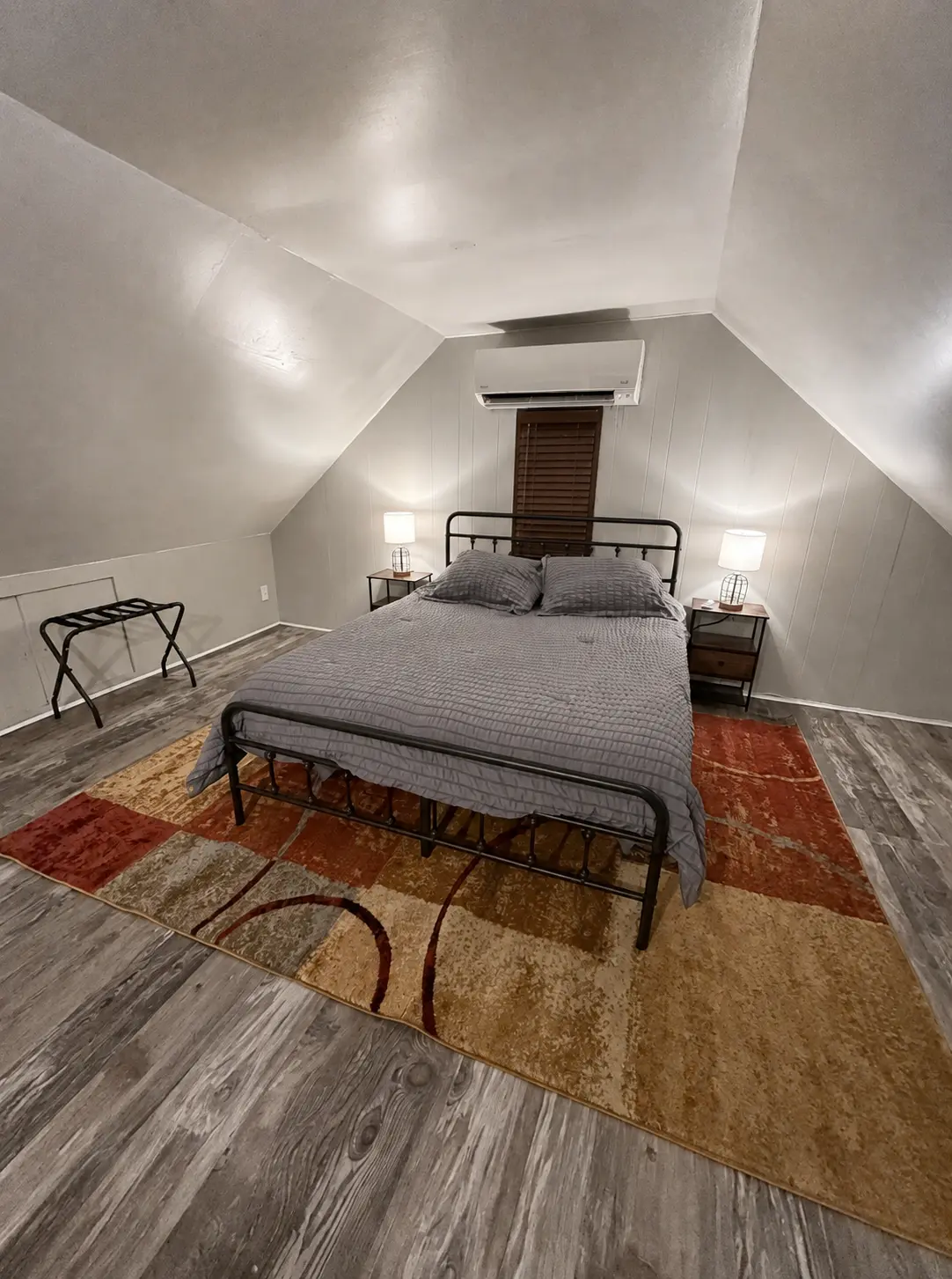 Upstairs bedroom with a black metal queen bed, nightstands with lamps and a patterned area rug