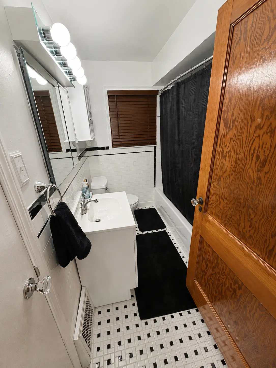 Main floor bathroom with white subway tile, vanity sink, mirror, bathtub with shower curtain and patterned tile floor