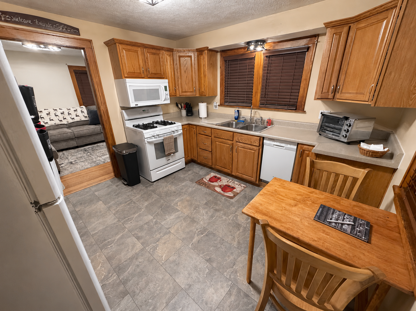 Kitchen with oak cabinets, gas range, microwave, dishwasher and a wood table with chairs